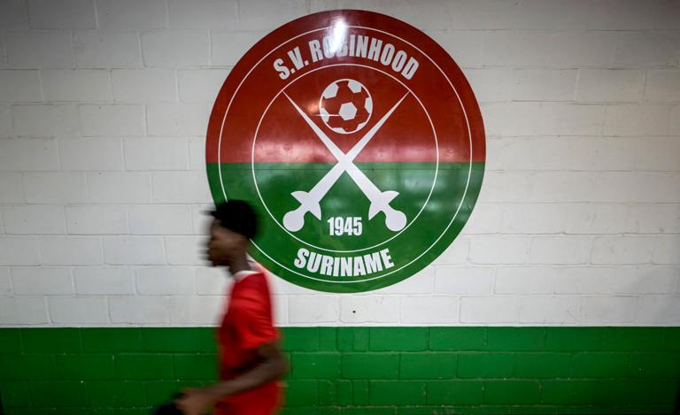A player of Sport Vereniging Robinhood football team walks in front of a club logotype at the end of a training session in Paramaribo on May 26, 2025. Suriname, although located in South America and a neighbor of Brazil, competes in the Concacaf qualifiers, where the three traditionally dominant countriesUnited States, Mexico, and Canadaautomatically qualify as hosts. With the World Cup expanding to 48 teams, in this football confederation of North America, Central America, and the Caribbean, which includes 41 federations, three direct spots and two playoff spots are up for grabs. (Photo by Juan BARRETO / AFP) (Photo by JUAN BARRETO/AFP via Getty Images)          